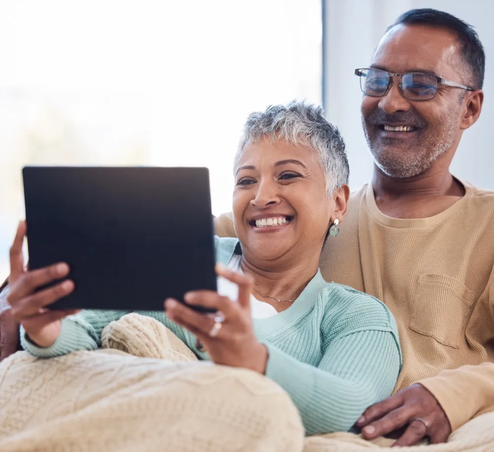 A couple relaxing together while reviewing their finances on a tablet